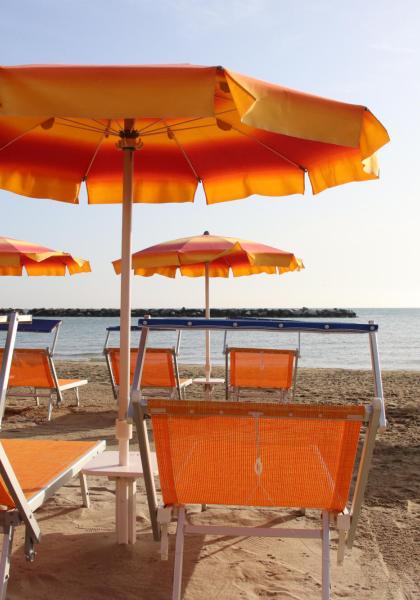 Spiaggia con ombrelloni arancioni e lettini, mare calmo sullo sfondo.