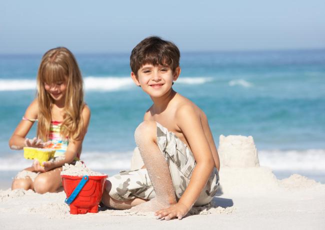 Children playing on the beach building sandcastles.