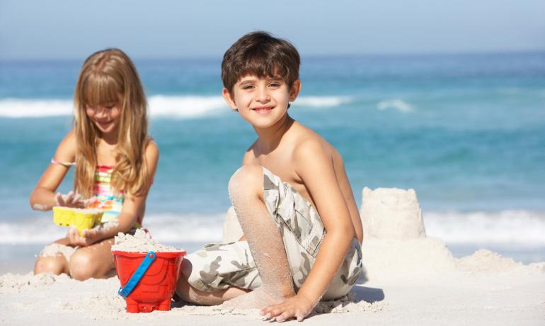 Children playing on the beach building sandcastles.
